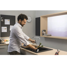 Homme lavant des légumes dans un évier de cuisine avec robinet