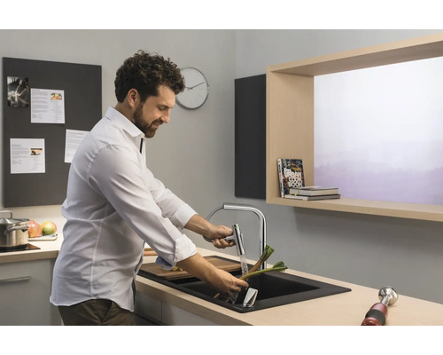 Mann wäscht Gemüse in einer Küchenspüle mit Armatur