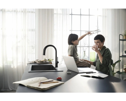 Moderne Küche mit dunkler Arbeitsplatte, Spüle und Armatur sowie Mutter und Kind