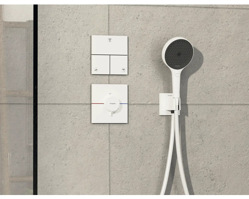 Ensemble de robinetterie de douche apparente avec douchette à main et éléments de commande sur un mur gris