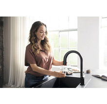 Femme remplissant un verre d''eau à un robinet de cuisine