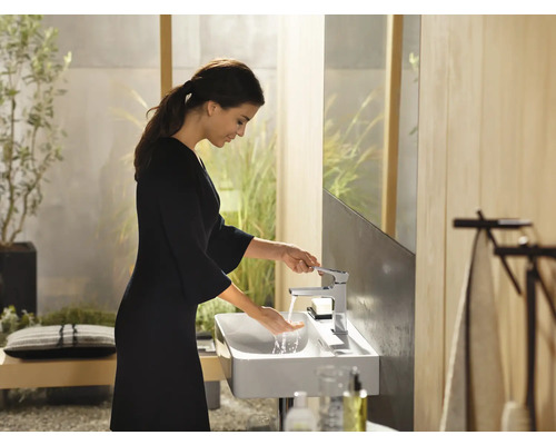 Frau wäscht sich die Hände im Badezimmer mit Waschbecken und Armatur