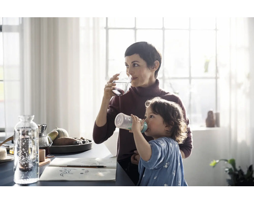 Szene in einem hellen Raum mit Mutter und Kind beim Trinken von Wasser