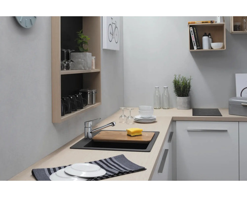 Küchenspüle mit Armatur, Schneidebrett und Geschirr in einer hellen Küche