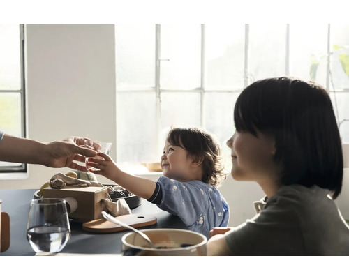 Helle Szene am Esstisch mit Kindern, die ein Glas Wasser bekommen.