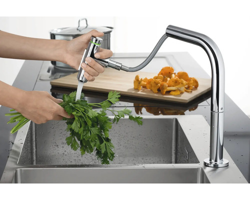 Küchenarmatur mit ausziehbarer Handbrause und Person beim Waschen von Kräutern