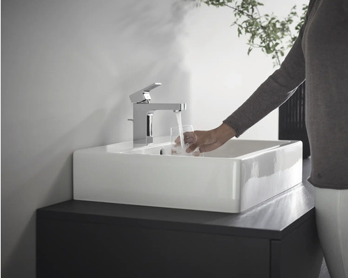 Personne remplissant un verre d''eau sur un lavabo avec robinet