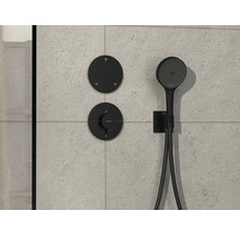 Schwarze Duscharmatur mit Handbrause an gefliester Wand