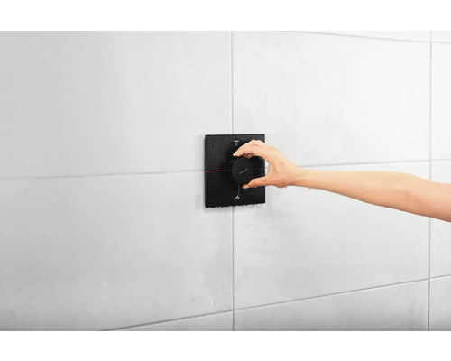 Installation d''un robinet de douche avec la main sur un mur carrelé blanc