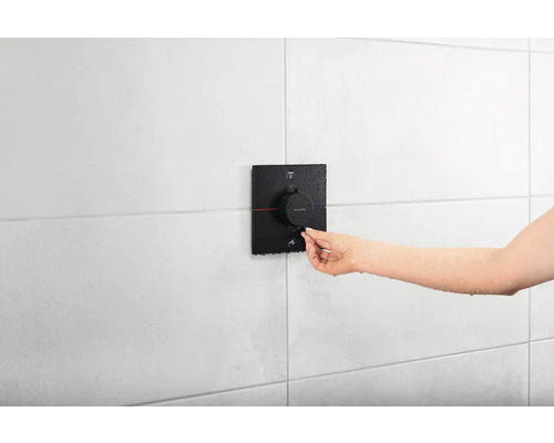 Une personne utilise un mitigeur de douche Hansgrohe dans la salle de bain