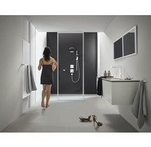 Helles Badezimmer mit Dusche, Waschbeckenunterschrank, Spiegel und Heizkörper.