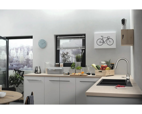 Helle Küche mit Spüle, Armatur, Arbeitsplatte, Küchenutensilien, Dekoration und Fenster.