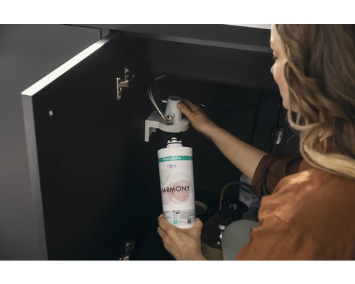 Frau wechselt den Hansgrohe Claro Harmony Wasserfilter unter der Spüle aus