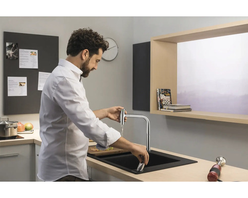 Mann steht an einer Küchenspüle und bedient eine Armatur.