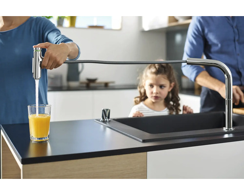 Une famille dans une cuisine lumineuse, la mère remplissant un verre avec un robinet avec un tuyau