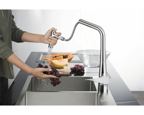 Frau wäscht Trauben unter einem Küchenarmatur mit herausziehbarer Brause