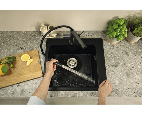 Schwarzes Küchenspülbecken mit Armatur und einem Mann, der den Wasserhahn bedient