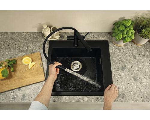 Évier de cuisine noir avec robinet extractible au design moderne sur un plan de travail, tandis que de l''eau coule dans l''évier.
