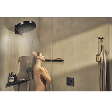 Frau unter einer Kopfbrause in einer modernen Dusche mit Armaturen