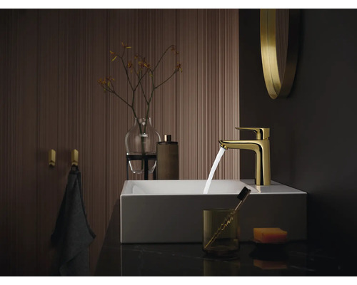 Badezimmer Waschbecken mit goldener Armatur, Handtuch und Accessoires