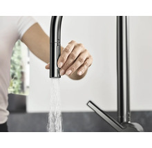 Frau bedient eine Küchenarmatur mit Wasserauslauf