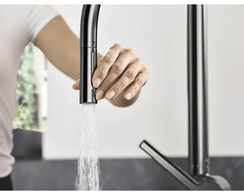 Femme actionnant un robinet de cuisine avec jet d''eau