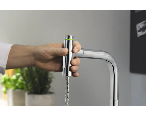 Eine Hand bedient einen verchromten Küchenarmatur mit Wasserauslauf.
