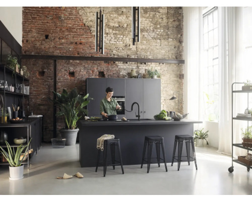 Moderne Wohnküche mit Kochinsel, Barhockern und Regalen vor einer Backsteinwand