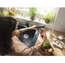 Frau befüllt einen Mixer mit Wasser an einem Spültisch mit Armatur in einer Küche.