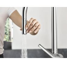 Frau bedient eine Küchenarmatur mit Wasserauslauf.