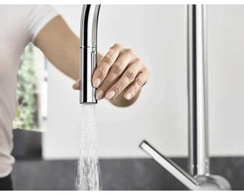 Femme actionnant un robinet de cuisine avec écoulement d''eau.