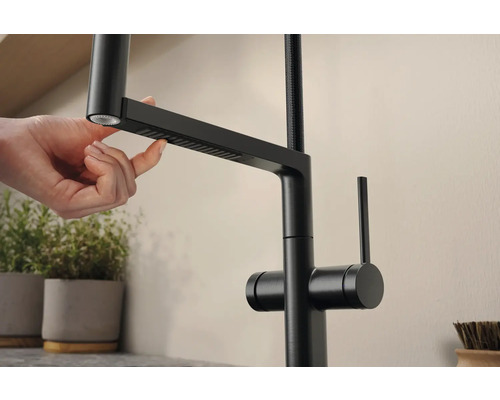 Nahaufnahme einer schwarzen Küchenarmatur mit ausziehbarer Brause, die von einer Hand bedient wird.