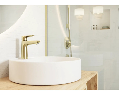 Vasque à poser avec robinet de lavabo doré dans une salle de bains claire.