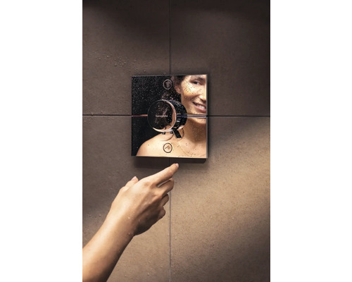 Une femme actionne un robinet de douche Hansgrohe au mur