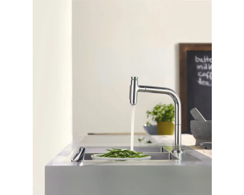 Küchenarmatur aus Chrom mit laufendem Wasser und Teller mit grünen Bohnen im Spülbecken