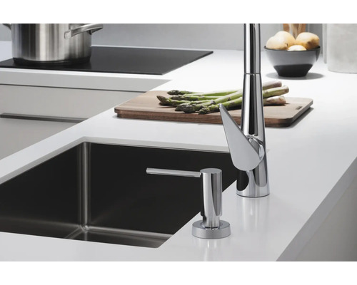 Scène de cuisine avec évier, robinet de cuisine et distributeur de savon sur un plan de travail.