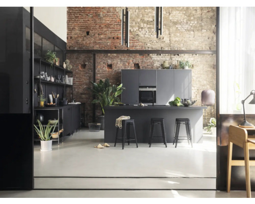 Offene Küche mit Kücheninsel, Stühlen und Regalen vor einer Ziegelwand