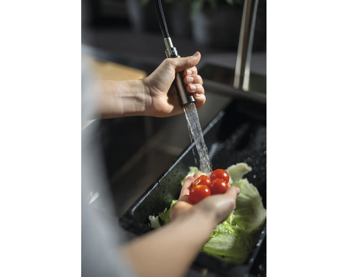 Person wäscht Tomaten und Salat in einem Spülbecken mit einer Küchenarmatur.