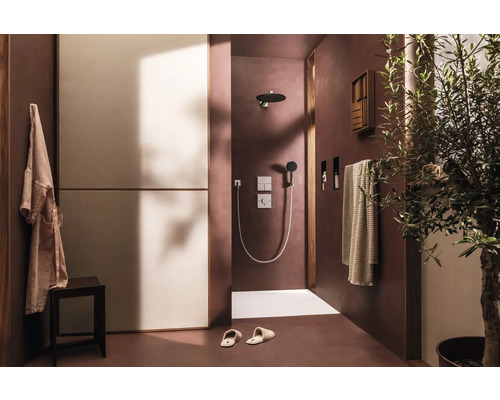 Badezimmer mit Dusche, Handtuch, Bademantel und Pflanze für eine entspannende Atmosphäre.