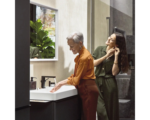 Helles Badezimmer mit Waschbecken, Spiegelschrank und zwei Frauen