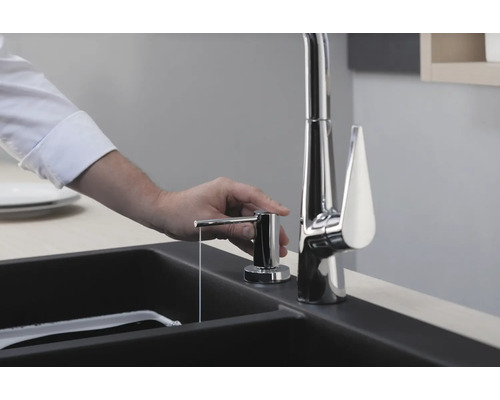 Une personne actionne un distributeur de savon à côté d''un évier avec robinet