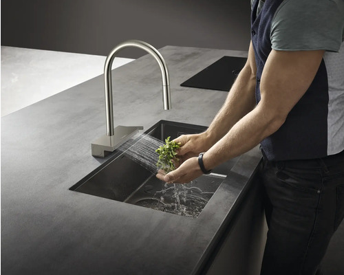 Eine Person wäscht Kräuter in einem Spülbecken mit einer Armatur.