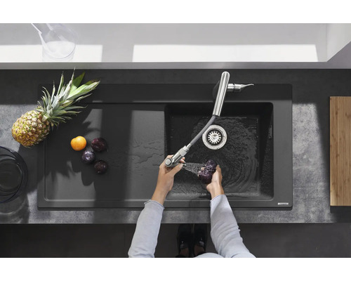 Spüle mit Armatur und Person wäscht Pflaumen