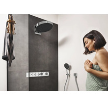 Moderne Dusche mit Kopfbrause, Handbrause und Armaturen sowie eine Frau, die in ein Handtuch gehüllt ist