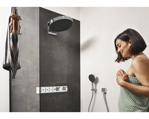 Douche moderne avec douche de tête, douchette et robinetterie ainsi qu''une femme enveloppée dans une serviette