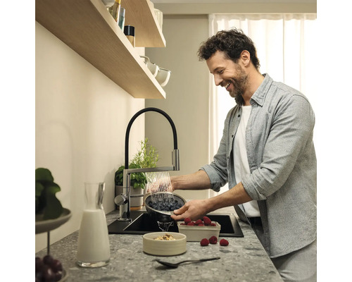 Homme lavant des baies dans un évier avec un robinet de cuisine
