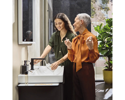 Helles Badezimmer mit Waschbecken, Armatur und zwei Frauen
