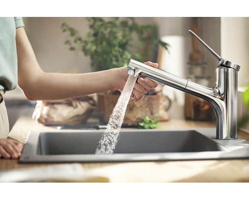 Femme utilisant un robinet d''évier avec douchette extractible dans la cuisine