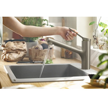 Eine Person bedient eine Küchenarmatur mit Wasserauslauf in einem modernen Küchenbereich.