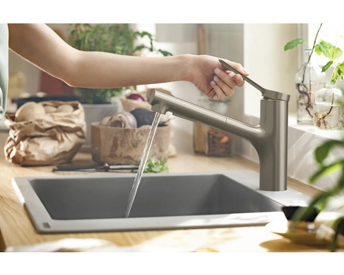 Une personne utilise un robinet de cuisine avec un jet d''eau dans une cuisine moderne.